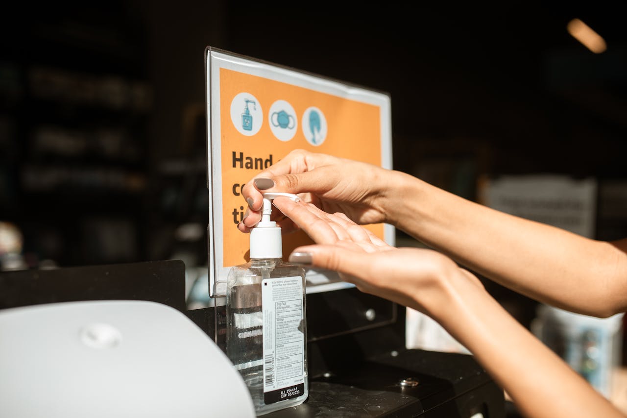 Person using hand sanitizer at a public station, emphasizing hygiene and safety.